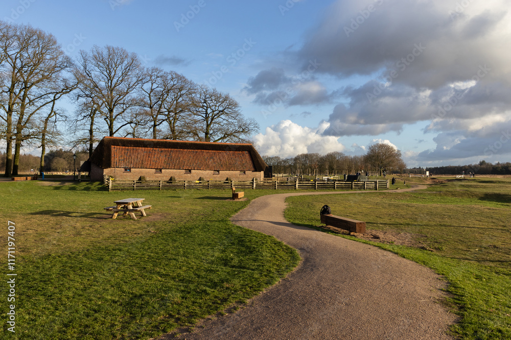 Obraz premium Sheep barn and footpath on the Ginkel Heath near Ede in Gelderland the Netherlands on a sunny winter day. This is the starting point for many walks on the heathland nature reserve.