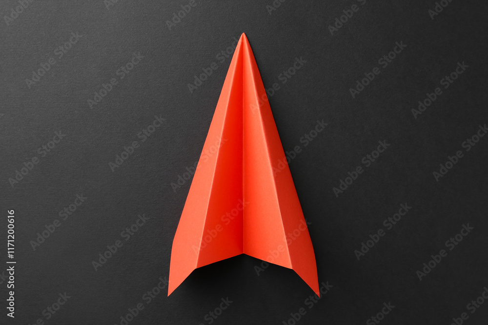 Fototapeta premium One handmade orange paper plane on grey background, top view