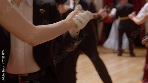 Several young couples are dancing in elegant costumes, dresses and gloves. They are cosplaying old dances from the 19th century.