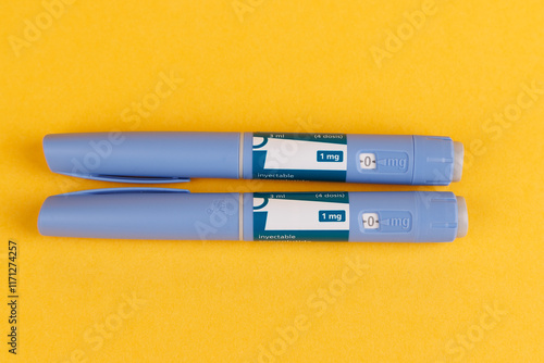 Glucose control medication pens with semaglutide on yellow background in top view photo