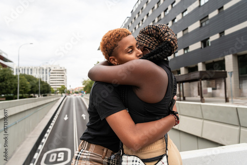 Loving LGBT multiethnic couple embracing on urban city street bridge photo