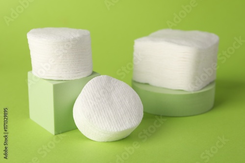 Clean cotton pads on green background, closeup photo