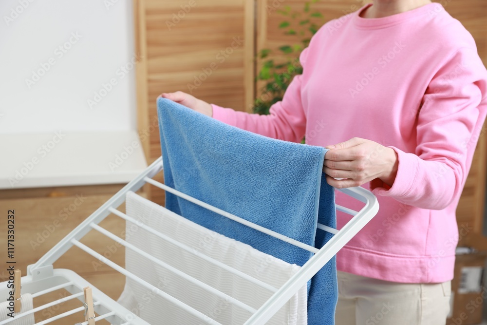 Woman hanging fresh clean laundry on drying rack at home, closeup Woman hanging fresh clean laundry on drying rack at home, closeup