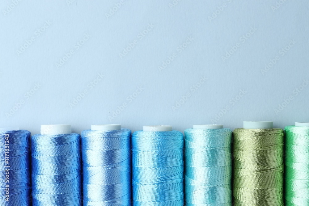Spools of colorful sewing threads on light background, flat lay. Space for text Spools of colorful sewing threads on light background, flat lay. Space for text