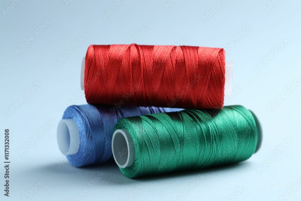 Spools of colorful sewing threads on light background, closeup
