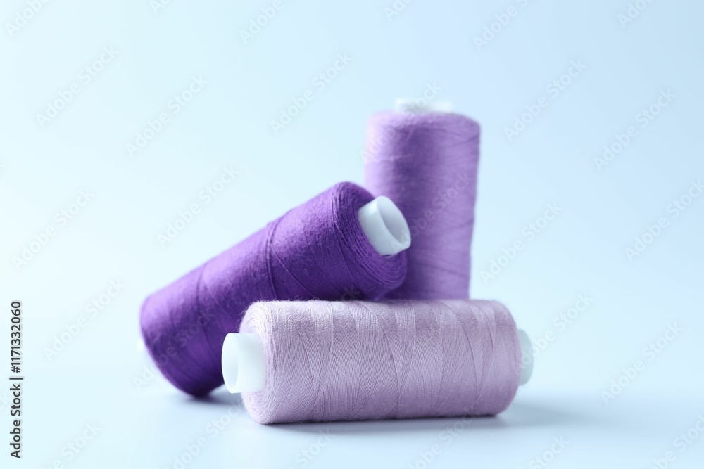 Spools of colorful sewing threads on light background, closeup Spools of colorful sewing threads on light background, closeup