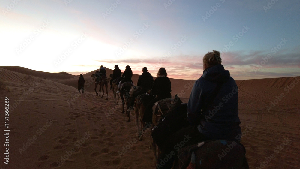Caravan going through the sand dunes in the Sahara Desert, Morocco - Merzuga - tourist visit the desert on camels during the holidays - adventure and freedom during a trip , safari - organized travel