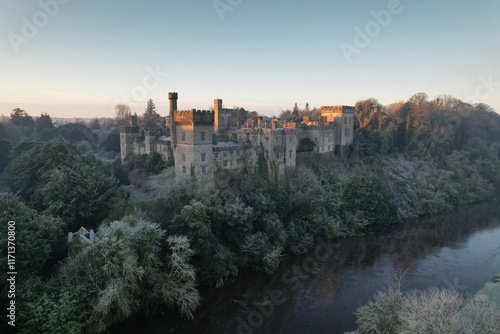 Aerial view of Lismore Castle in County Waterford, Ireland, on a frosty winter morning, showcasing its stunning Gothic Revival architecture against a cold, atmospheric landscape photo