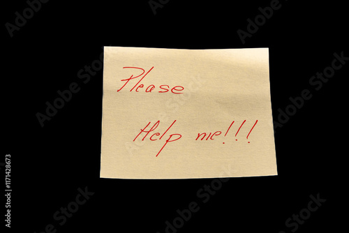 Yellow adhesive paper, similar to a Post-it note, on a black background with the words “Please Help me” and three exclamation marks handwritten in red ink.