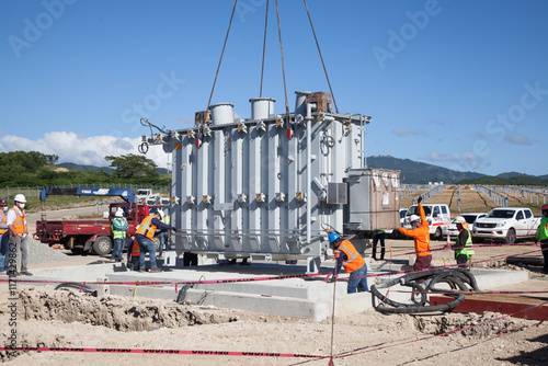 Men's installing a transformer in a solar farm substation 
