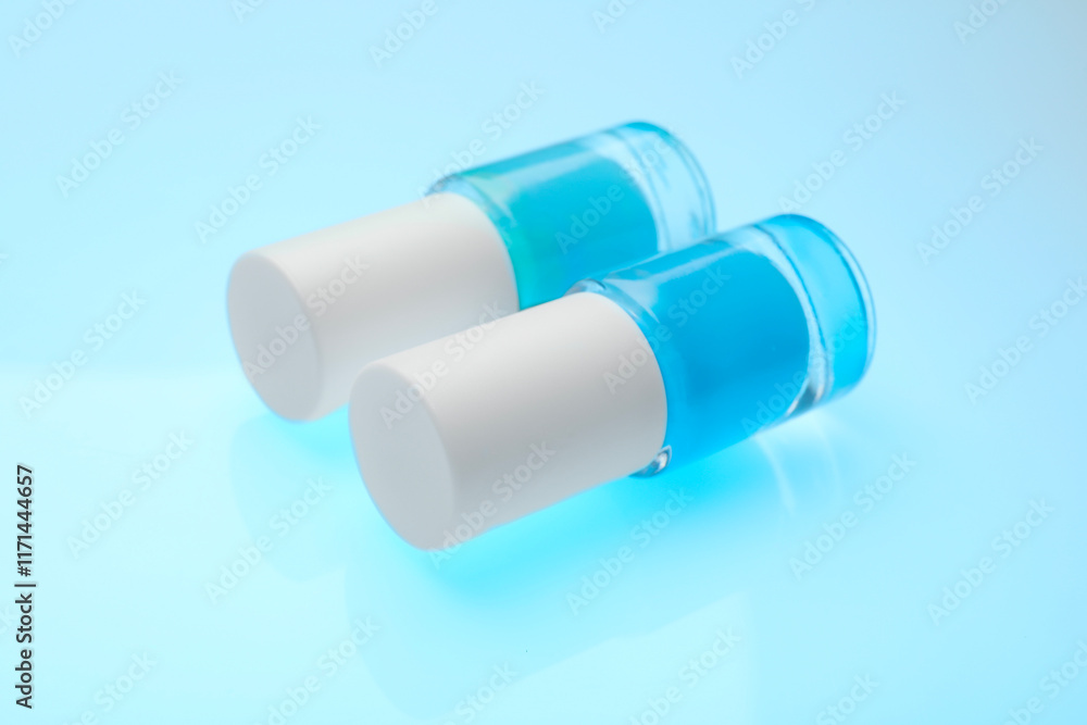 Nail polish in bottles on light blue background, closeup Nail polish in bottles on light blue background, closeup