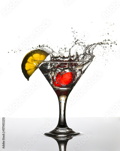 cubito de hielo cayendo en una copa de bebida y un trozo de limon