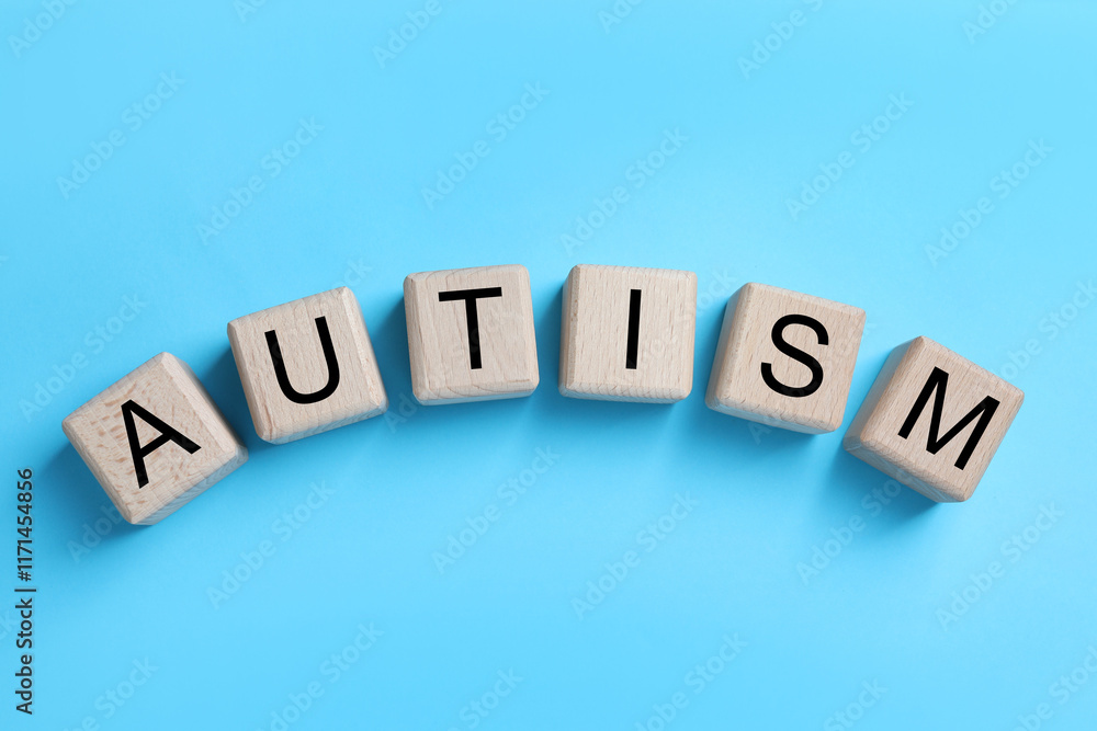 Obraz premium Word Autism made of wooden cubes on light blue background, top view