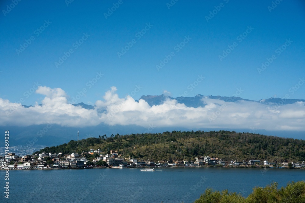 Scenic lakeside town with lush hills and blue sky. Scenic lakeside town with lush hills and blue sky.