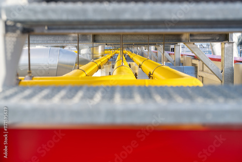 Foto Supply of industrial gas yellow piping with dew drops on racks over roof of manu