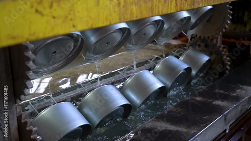 Close up view of dipping hanged metal pieces in the electropaint tank for the cataphoresis or paint process on the automated conveyor in a factory.