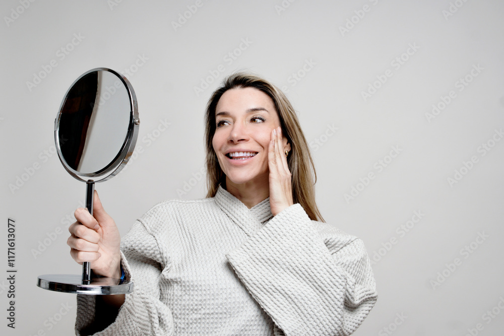 woman in bathrobe looking at herself in the mirror woman in bathrobe looking at herself in the mirror