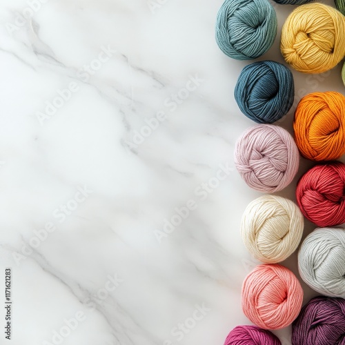 Collection of colorful yarn balls arranged on a marble surface for crafting a...
