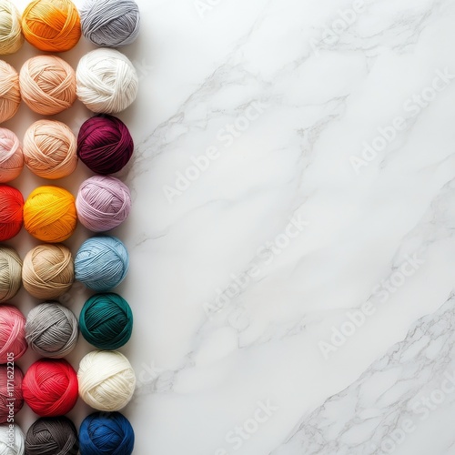 Collection of colorful yarn balls arranged on a marble surface for crafting a...