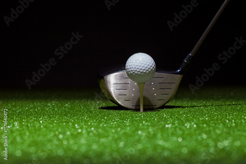 Photography Low angle selective focus of golf ball and driver on a green with black backgrou