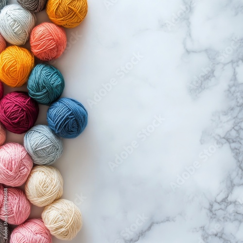 Collection of colorful yarn balls arranged on a marble surface for crafting a...