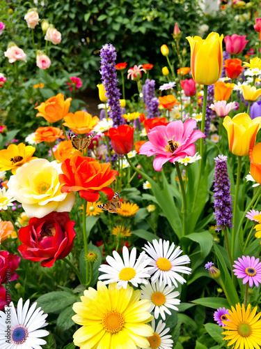 A vibrant garden in full bloom, showcasing an array of colorful flowers such as roses, tulips, and daisies. Butterflies and bees flit gracefully among the blossoms, photo