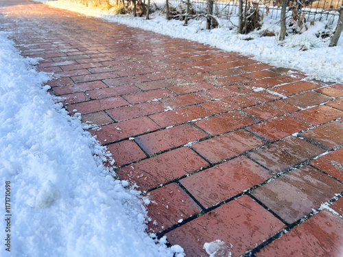 An icy pedestrian path sidewalk in winter with snow and sand