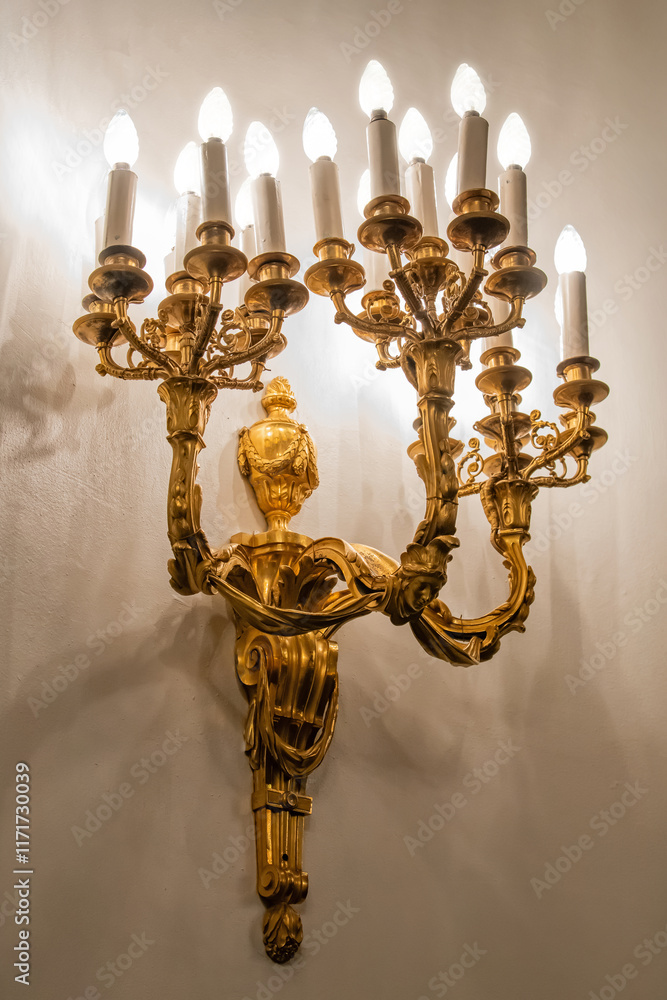 Antique gilded wall lamp in the shape of a candlestick in palace baroque style. Antique gilded wall lamp in the shape of a candlestick in palace baroque style.