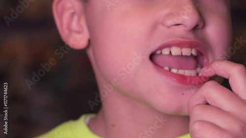 A boy rocks a baby tooth in close-up