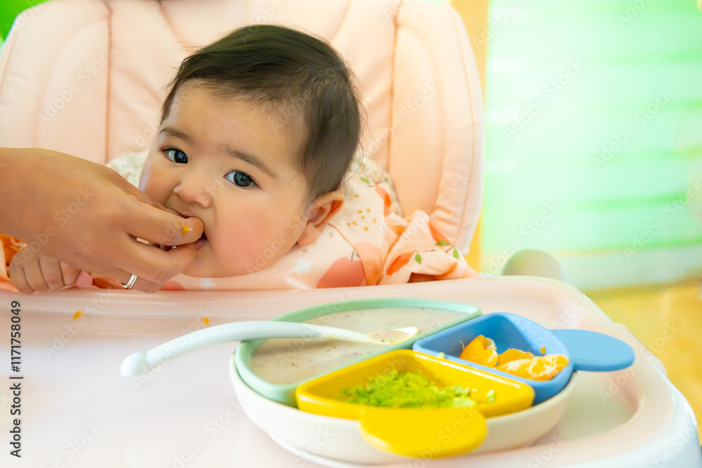 Cute white baby eating healthy food at home in his highchair, hand fed by Mama's BLW or baby led weaning method. Colorful plate Harvard method fruit, avocado, oatmeal, protein.... Cute white baby eating healthy food at home in his highchair, hand fed by Mama's BLW or baby led weaning method. Colorful plate Harvard method fruit, avocado, oatmeal, protein....