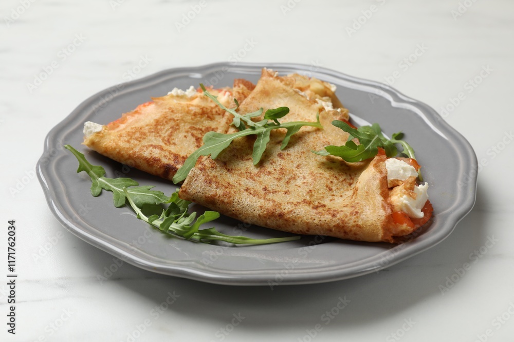 Delicious crepes with salmon, cream cheese and arugula on white marble table, closeup Delicious crepes with salmon, cream cheese and arugula on white marble table, closeup