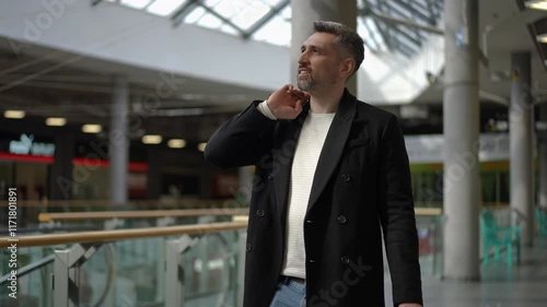 Wallpaper Mural Black Friday discounts and sales. A cheerful man holding multiple shopping bags walks energetically through a brightly lit mall, enjoying The sunlight streaming through the glass roof highlights the Torontodigital.ca