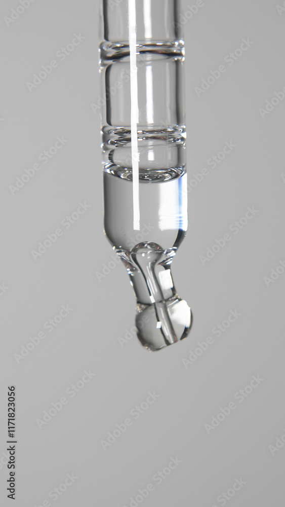 Transparent pipette on a white background: A macro shot shows a pipette with a drop of transparent face serum, reflecting purity and minimalism in skincare. Transparent pipette on a white background: A macro shot shows a pipette with a drop of transparent face serum, reflecting purity and minimalism in skincare.
