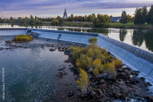 Autumnal river scene with a dam. Water cascades over the dam, reflecting the surrounding fall foliage and the Salt Lake Temple. Snake River, Idaho Falls, Idaho, USA. photo