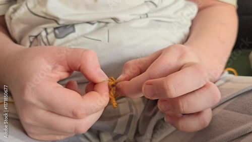 Girl untangling knot, tangled threads, correcting mistake. Close-up of children's hands doing handicrafts. Development of skills, fine motor skills, creativity, development of attention perseverance.