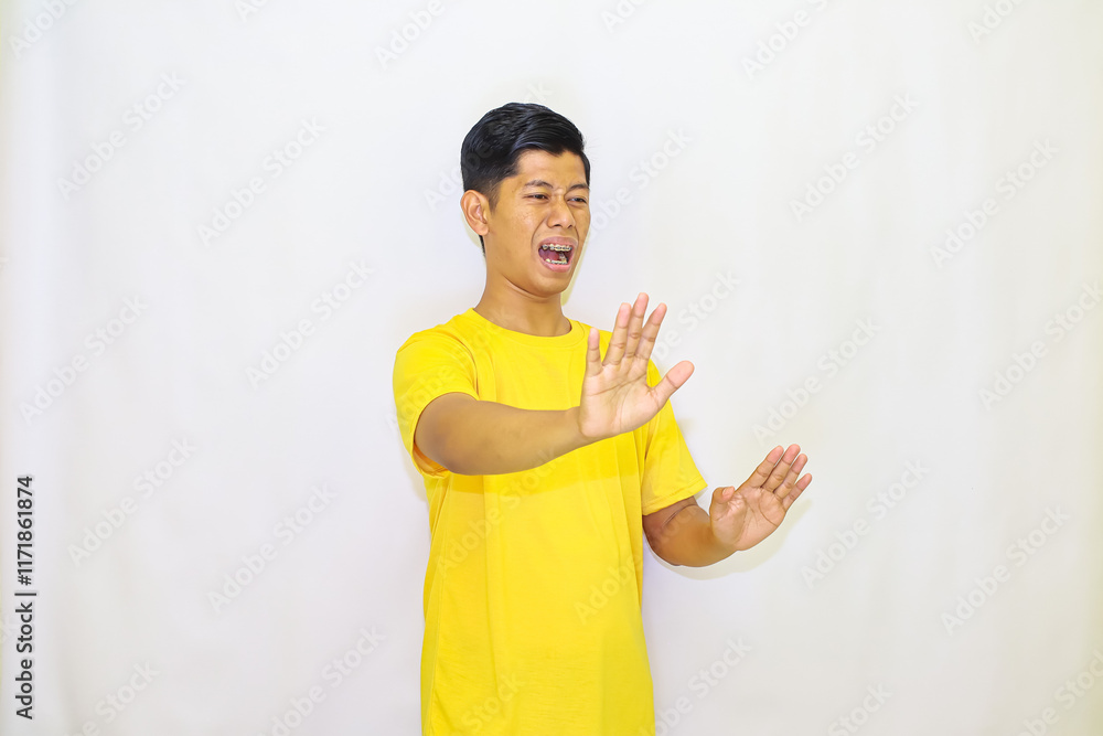 A man in a yellow shirt expresses disgust and rejection with raised hands against a white background, showing an obvious dislike for something, A man in a yellow shirt expresses disgust and rejection with raised hands against a white background, showing an obvious dislike for something,