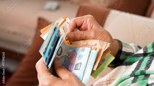 A bundle of euros in the hands of an elderly pensioner. The concept of financial security in old age.