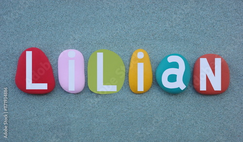Lilian, feminine given name composed with multi colored hand painted stone letters over green sand