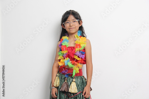 5 year old Latina brunette girl with glasses and Hawaiian skirt enjoys dancing and does Hawaii dance steps very happy and excited photo