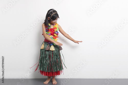 5 year old Latina brunette girl with glasses and Hawaiian skirt enjoys dancing and does Hawaii dance steps very happy and excited photo