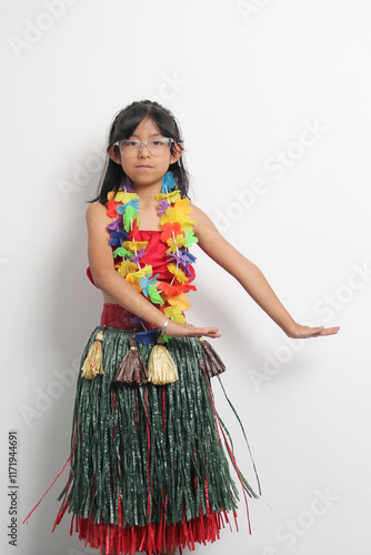 5 year old Latina brunette girl with glasses and Hawaiian skirt enjoys dancing and does Hawaii dance steps very happy and excited photo