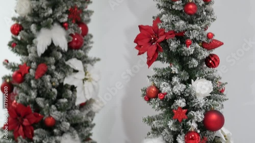 Red gift box tied with white satin ribbon. Present under tree. Christmas tree decorations on branches of Artificial Christmas tree. New Year celebration concept. December 31, 2024 - Pula, Croatia