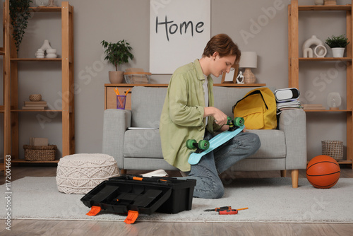 Male student fixing skatebo...