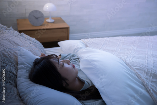 Obraz na płótnie 眠りにつく女性　ベッドの睡眠や寝不足、不眠などの寝付けないネガティブのイメージ　