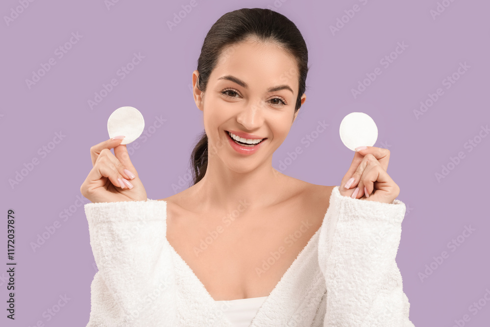 Beautiful young happy woman in bathrobe with cotton pads on purple background Beautiful young happy woman in bathrobe with cotton pads on purple background