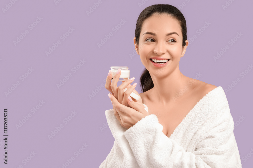 Beautiful young happy woman in bathrobe with jar of cream on purple background Beautiful young happy woman in bathrobe with jar of cream on purple background