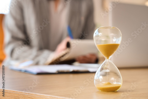 Hourglass on desk against b...