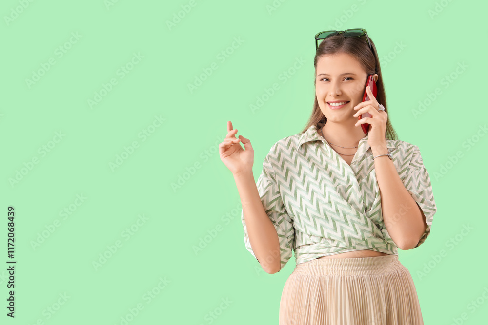 Smiling young woman talking by mobile phone on green background Smiling young woman talking by mobile phone on green background