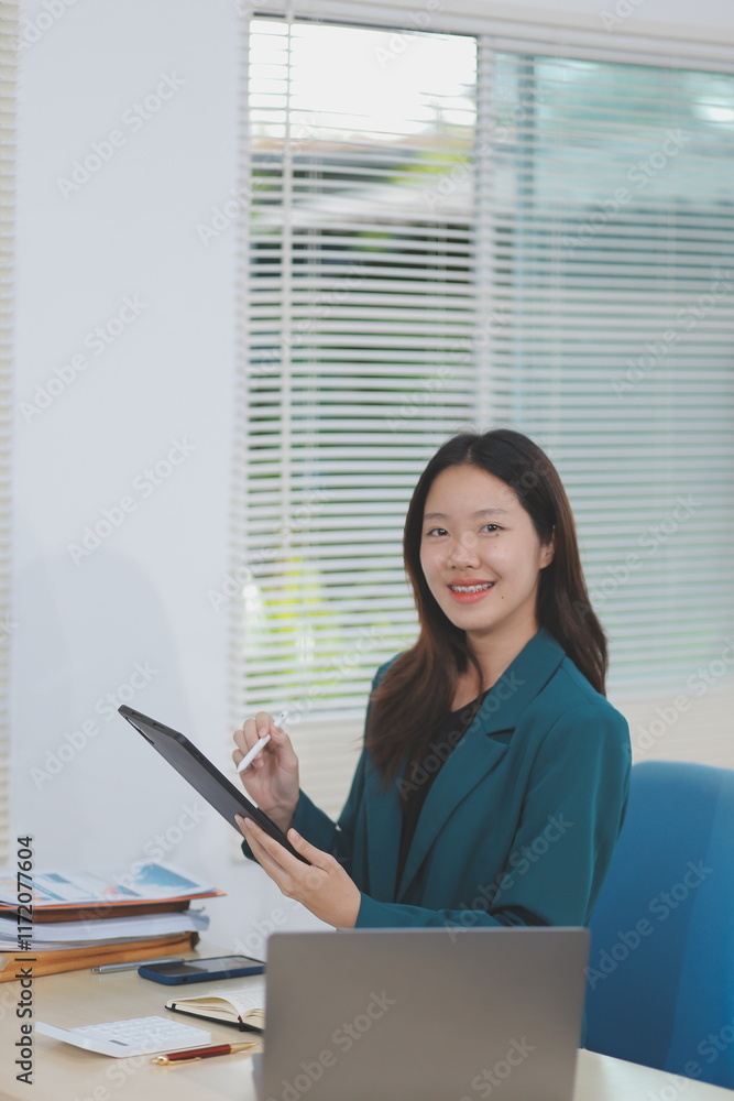 Obraz premium Asian professional businesswoman working on tablet computer in a corporate office