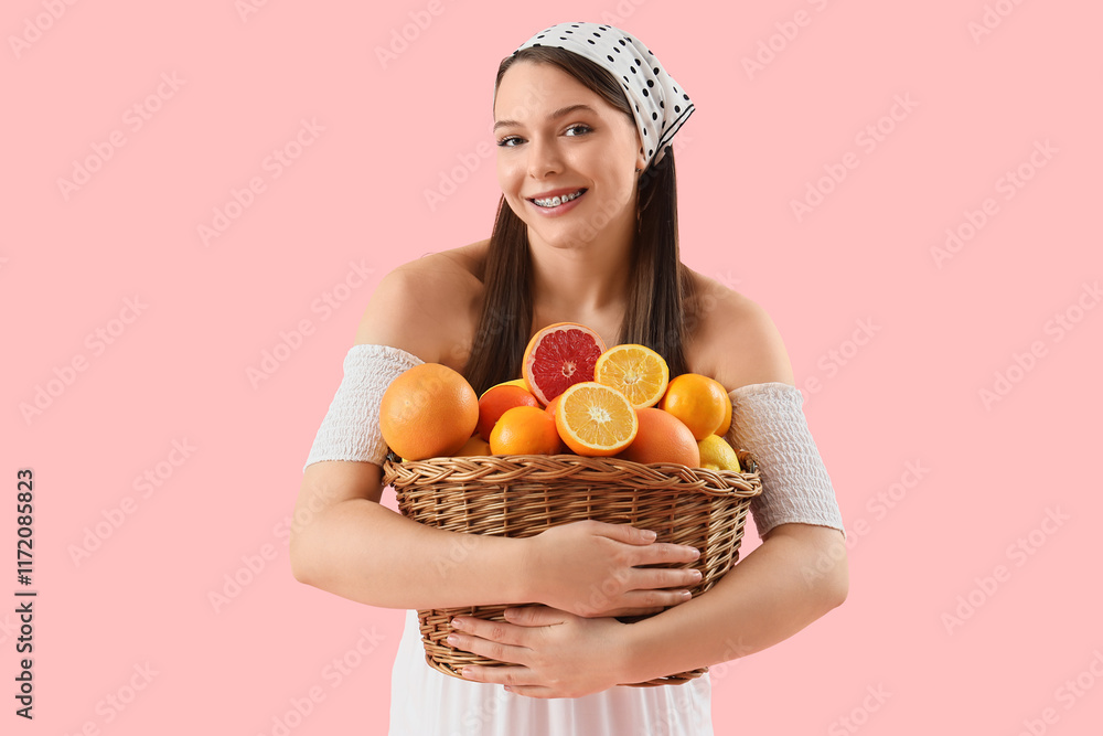 Young woman holding basket with citruses on pink background Young woman holding basket with citruses on pink background